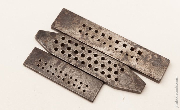 3 antique drawplates for making wire. They are wide, flat bars of steel with an array of holes slowly decreasing in size