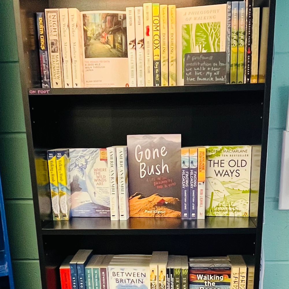 A bookshelf of books about nature and walking. Book titles include A Philosophy of Walking, Gone Bush, The Old Ways, Where the Wild Winds Are, Between Britain.