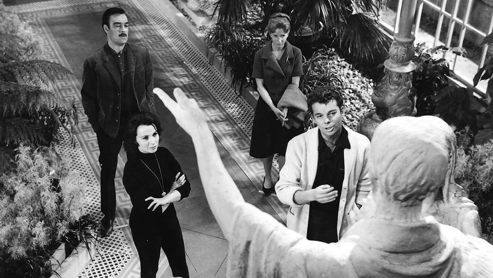 Four people staring at a statue