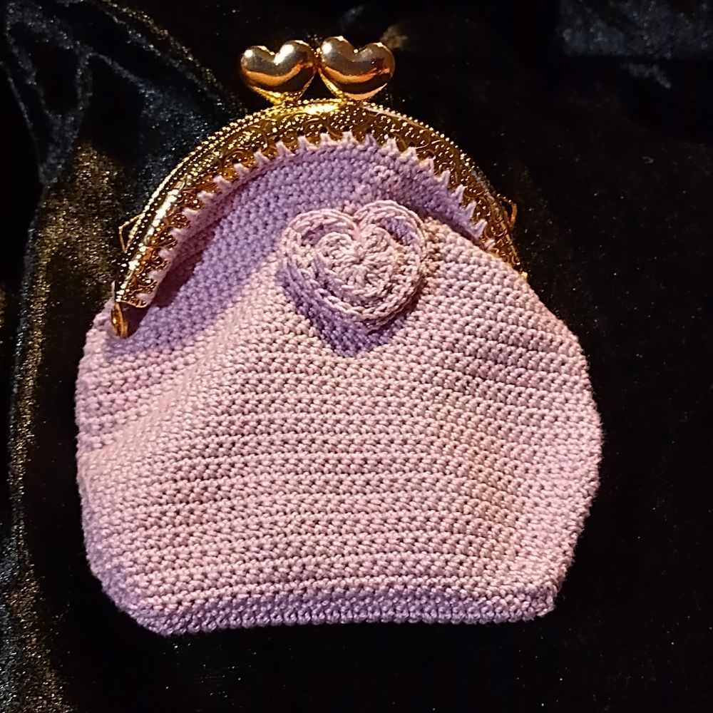 A light purple crocheted purse with gold hearts clasp and layered hearts decoration.