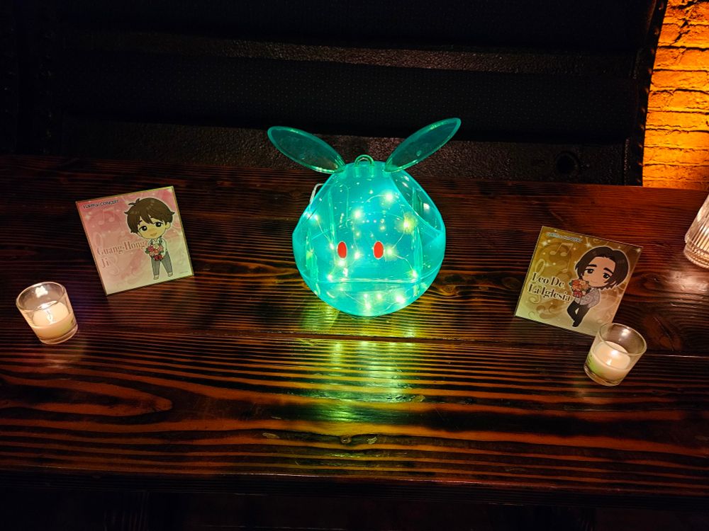 A translucent Haro from Gundam glows with LED lights. Drawings of Leo and Guang Hong sit on a table.