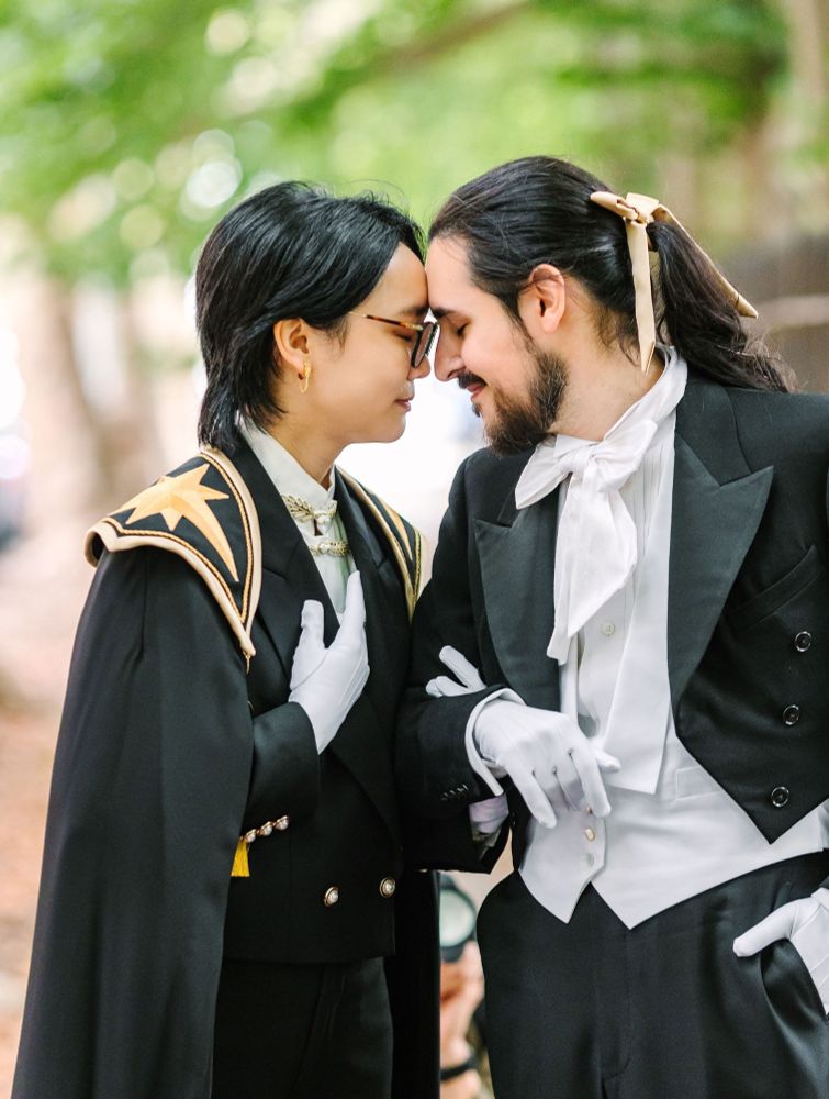 Two grooms hold each other at the elbow and touch foreheads in their ceremony clothes. (Photo by Maya Lovro Photography)