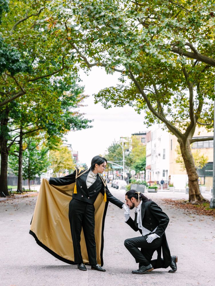 One groom kneels before the other on a Brooklyn street. (Photo by Maya Lovro Photography)