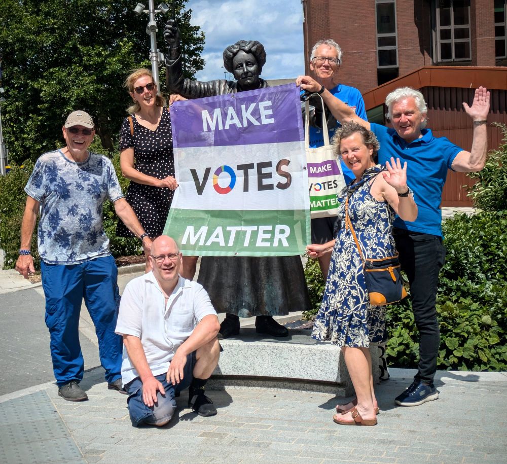 MVM Northwest Surrey local group with the statue of local suffragette Dame Ethel Smyth holding a  'Make Votes Matter' banner. Smiles and sunshine - campaigning for a brighter future with fair votes everywhere.