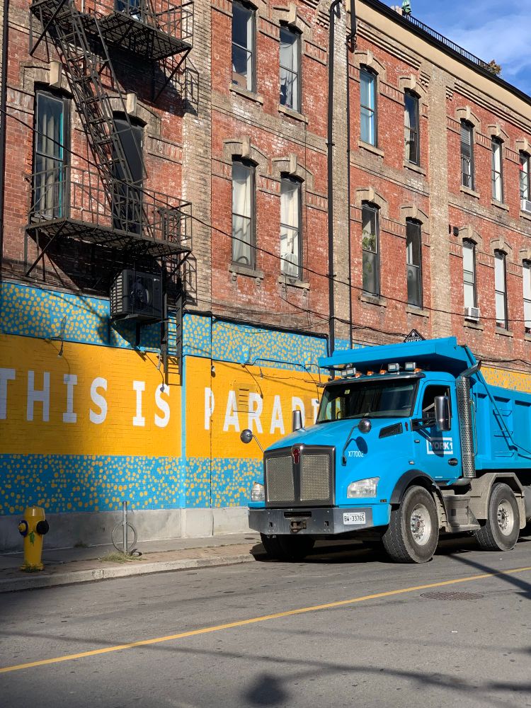 A blue truck against a wall with a blue and orange ad