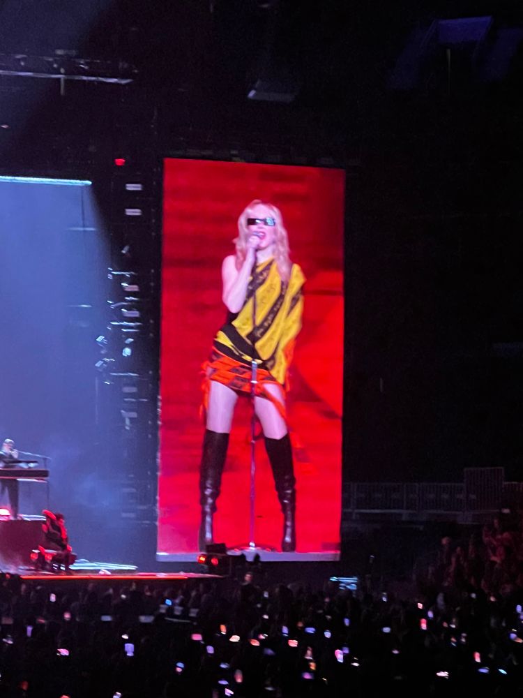 Kylie in the big screen in a yellow and orange outfit 
