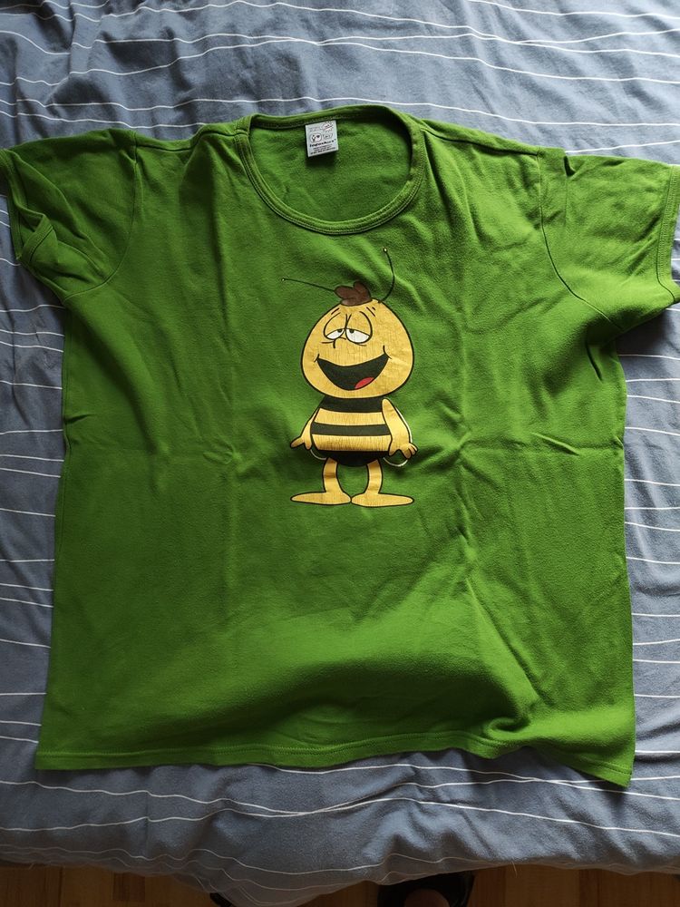 Ein grünes T-Shirt mit der Comic-Biene Willi auf einem blauen Untergrund 