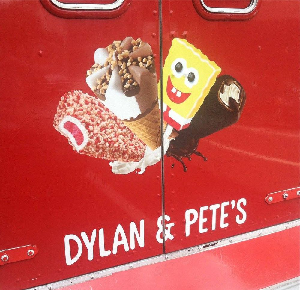 back of a red ice cream truck, with a variety of ice cream pops painted on it (strawberry crunch, drumstick, Spongebob, klondike). Caption painted in white reads "DYLAN & PETE'S"
