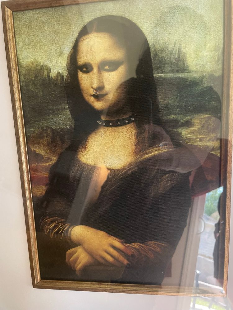 A framed print of the Mona Lisa with a septum ring, gothic makeup, and a choker.