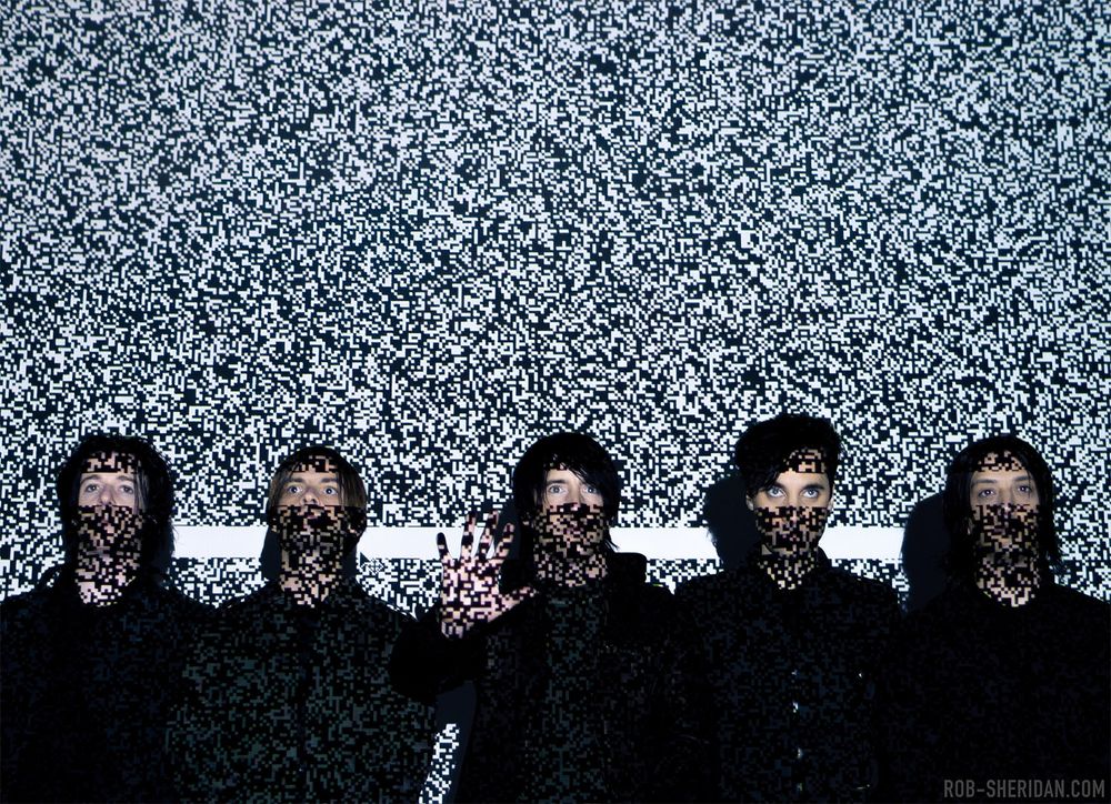 Nine Inch Nails photographed by Rob Sheridan in 2005 with blocky digital static projected onto them. L to R: Aaron North, Alessandro Cortini, Trent Reznor, Jerome Dillon, Jeordie White