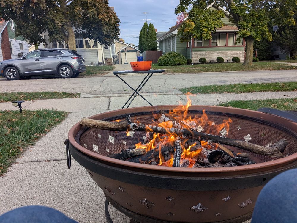 A fire pit with a bowl of Halloween candy in the distance.