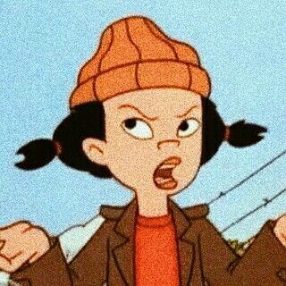 Personagem do desenho "Hora do Recreio". Cabelos pretos, maria chiquinha, gorro laranja. Blusa vermelha e casaco marrom. Pele clara. Esse desenho eu não conheço. 