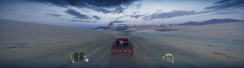 The Magnum Opus driving on an open road towards some rocky outcrops