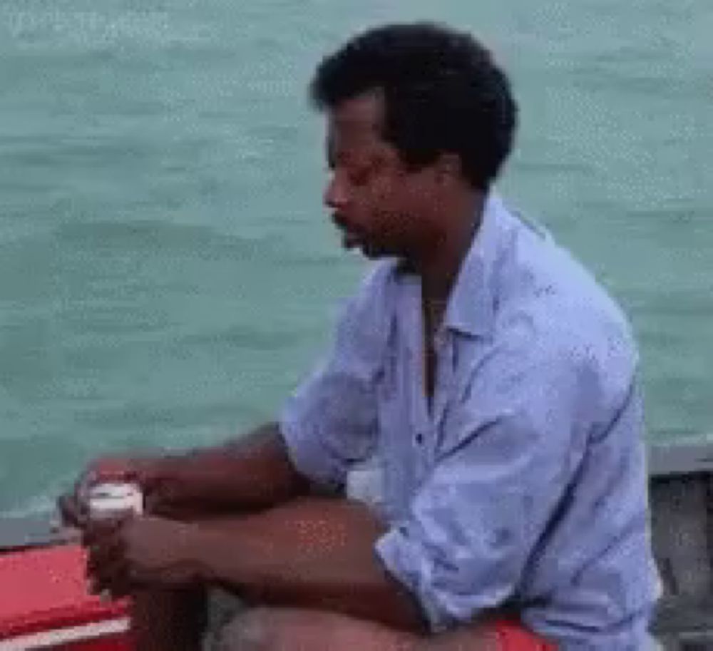 a man is sitting on a boat in the water holding a can of beer .