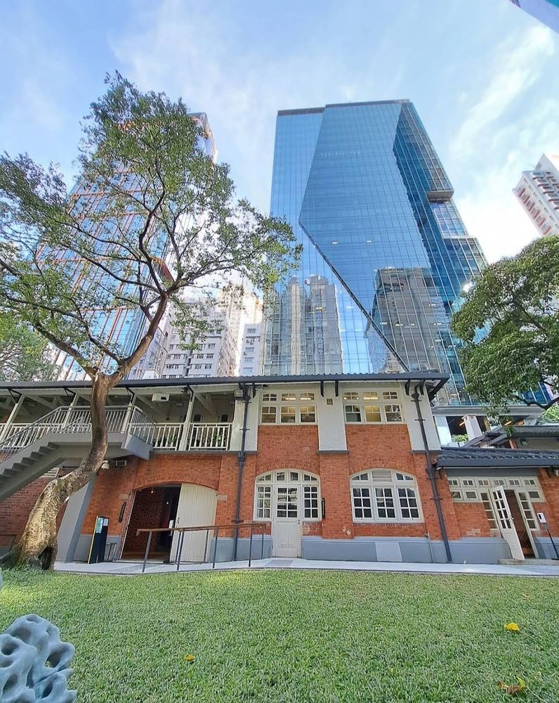 Vue en trois layers : pelouse verte impeccable (si on aime) au premier plan, façade de briques au second, gratte-ciels infinis tirant la perspective vers le ciel bleu au troisième plan, reflets dabs leurs façades miroir. Et le ciel bleu :)