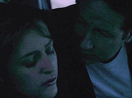Mulder and Scully are in a car. It's dawn. Scully is fast asleep. Mulder kisses her softly on the cheek then pauses to look at her. She doesn't wake up. 