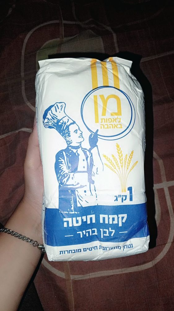Rana’s hand holding a kilo of flour against a brown blanket