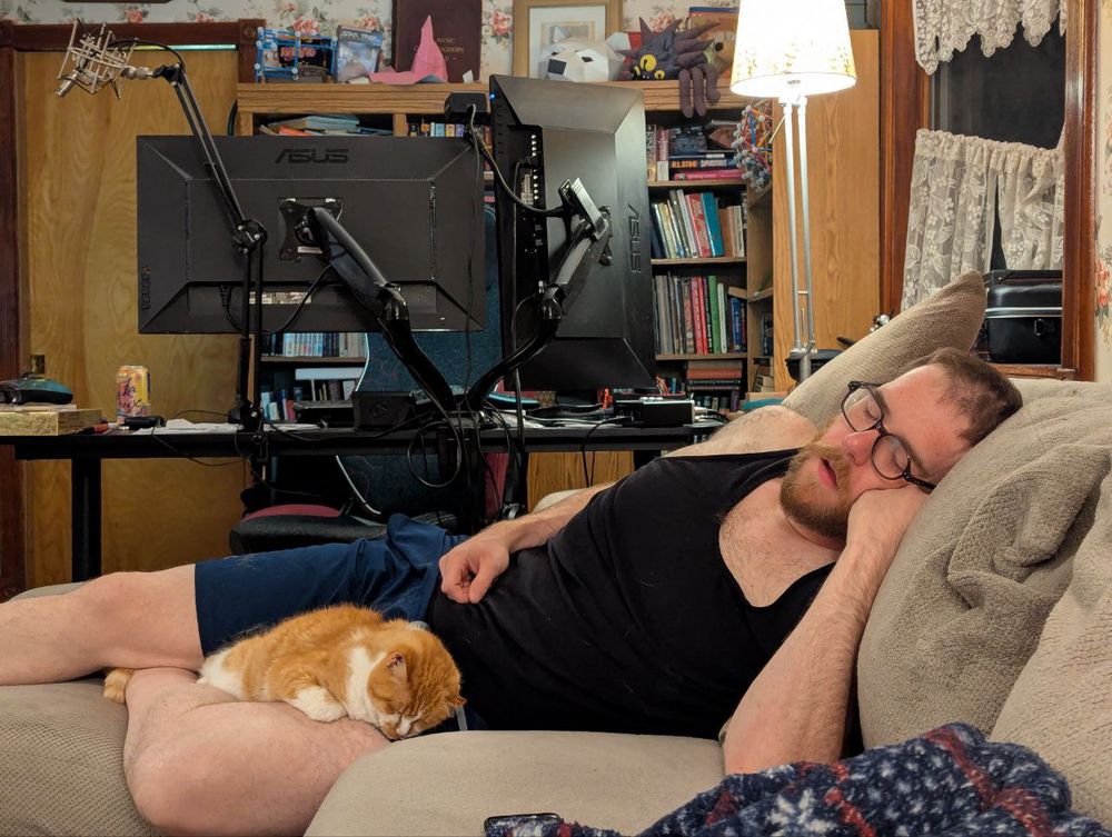 Me sleeping on the couch with my elderly cat sleeping in my lap