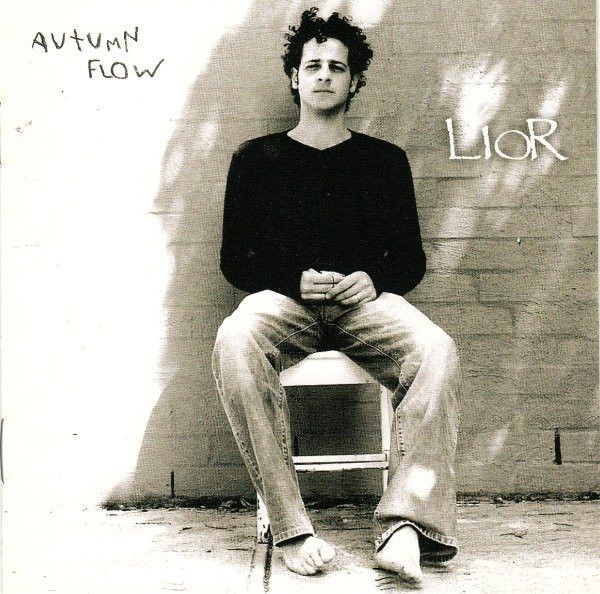 Album cover for Lior's Autumn Flow. Black and white picture of Lior sitting on a chair, barefoot, in front of a brick wall