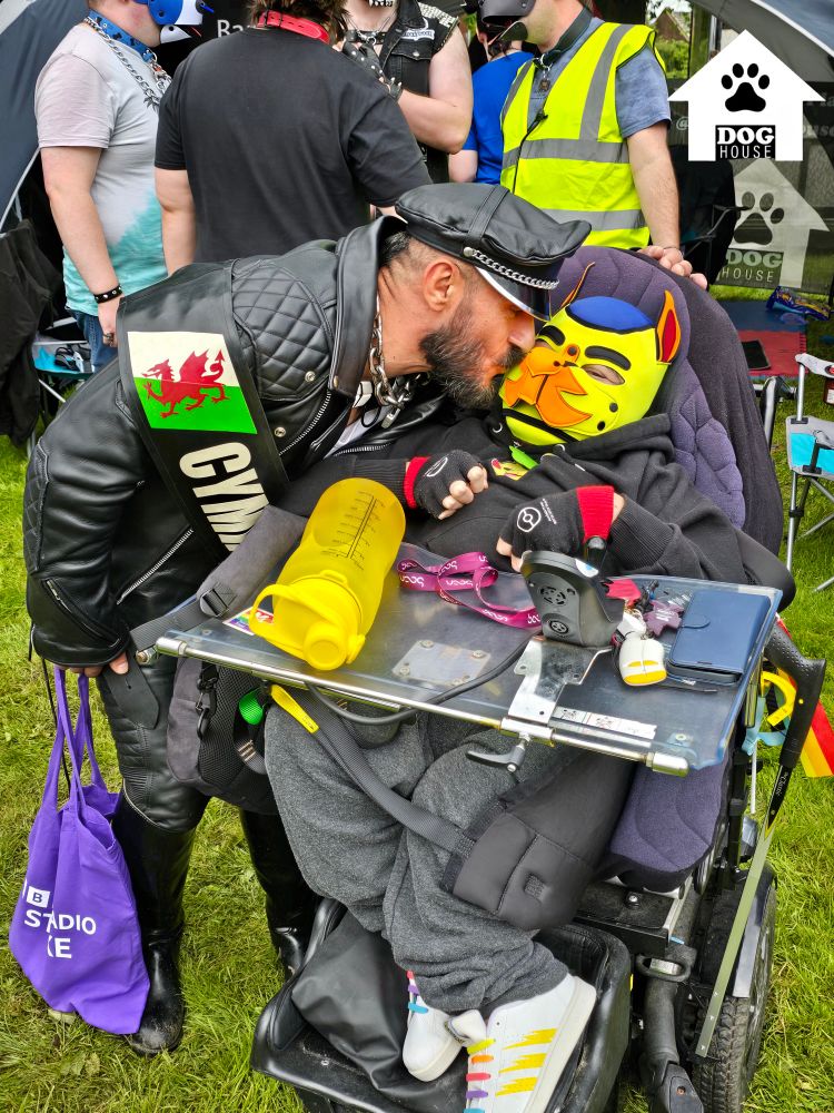 Disabled pup being kissed by a man in all black leather