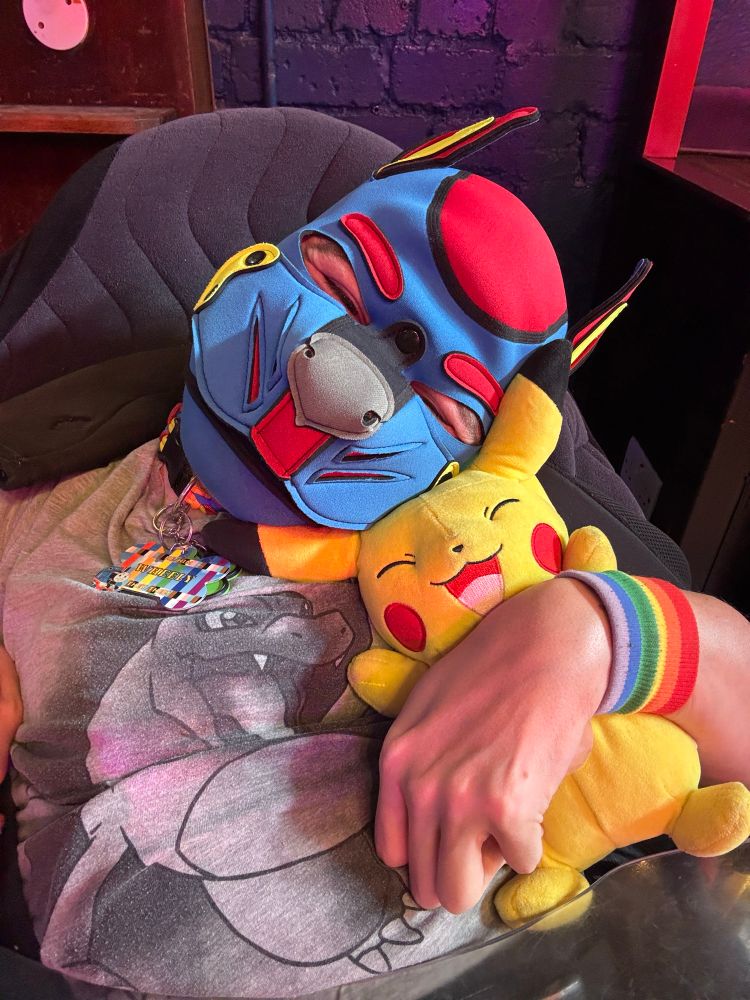 Disabled pup in a blue and red hood, hugging a Pikachu plushie 