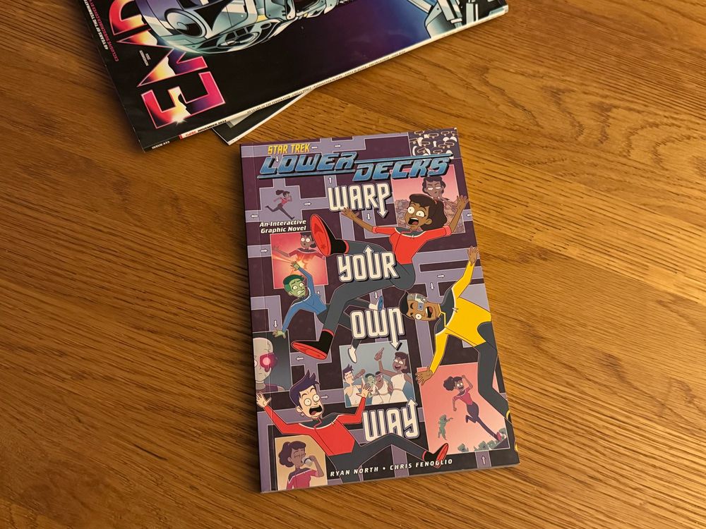 A copy of the Lower Decks “Warp Your Own Way” book by Ryan North and Chris Fenoglio is sitting on a table. Last month’s Empire film magazine is trying to get into shot at the top of the frame. It’s probably jealous. 