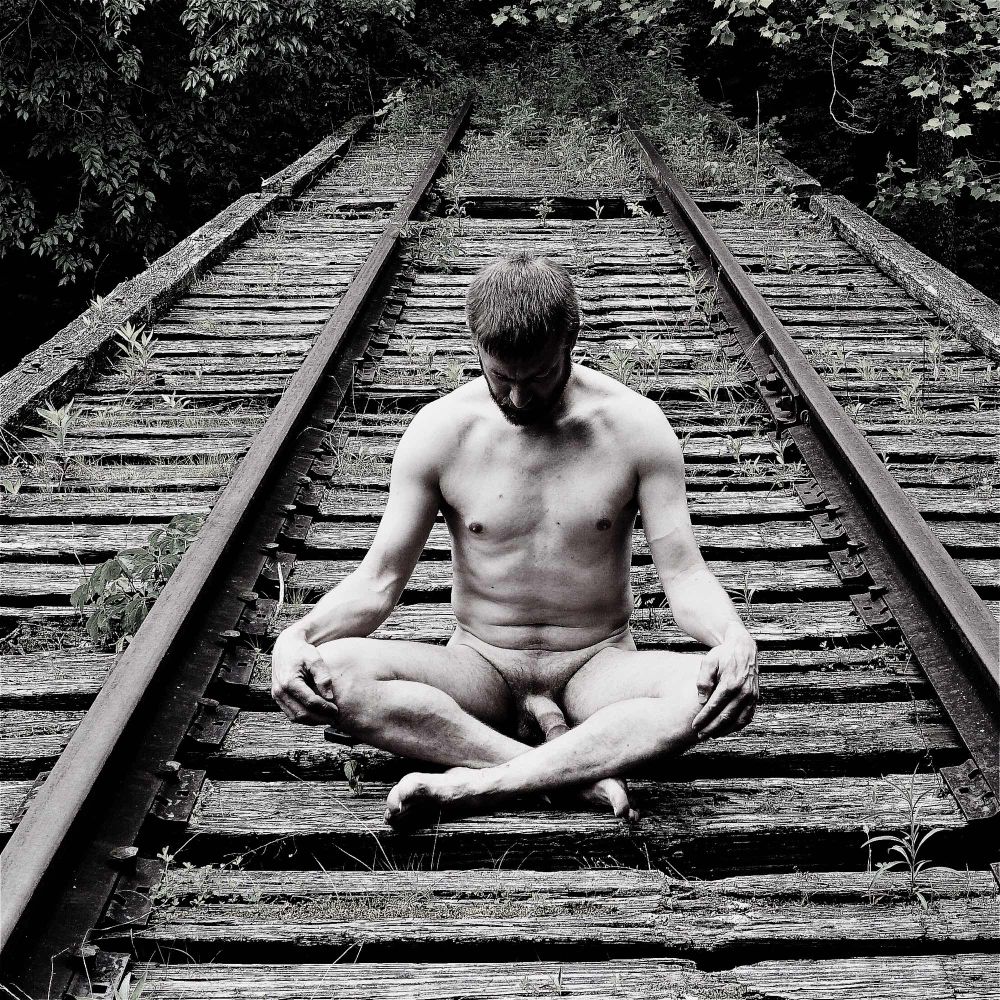 Me sitting nude cross legged on an abandoned railroad bridge 