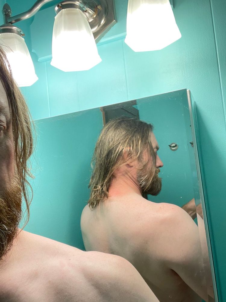 A selfie of me showing that my hair is down to my shoulders as I grow it out.