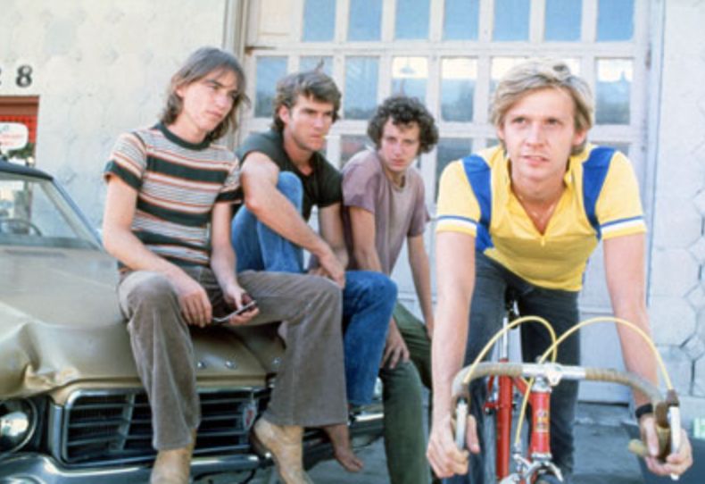 Still from the 1979 film "Breaking Away," with (from left) Jackie Earle Haley, Dennis Quaid, Daniel Stern (sitting on the hood of a beat-up car), and Dennis Christopher (on bike)