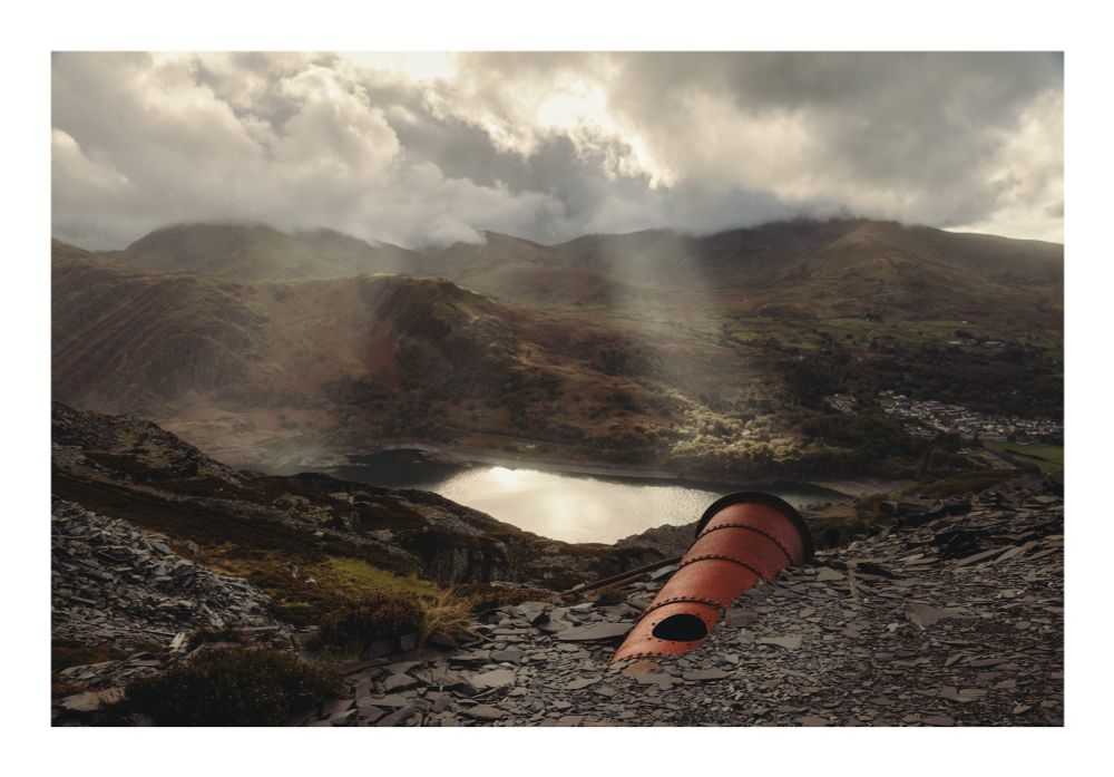 Am image of a pipe in front of mountains with shafts of sunlight breaking through clouds