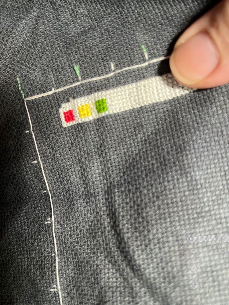 A close up of cross stitch on 18 count cloth, which is a stitch so small it would take a block of 20 of them to be as big as the thumbnail in frame. its modeled  on the window bar of a mac computer