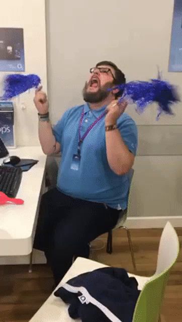 a man in a blue shirt is sitting at a desk with a pepsi sign on the wall