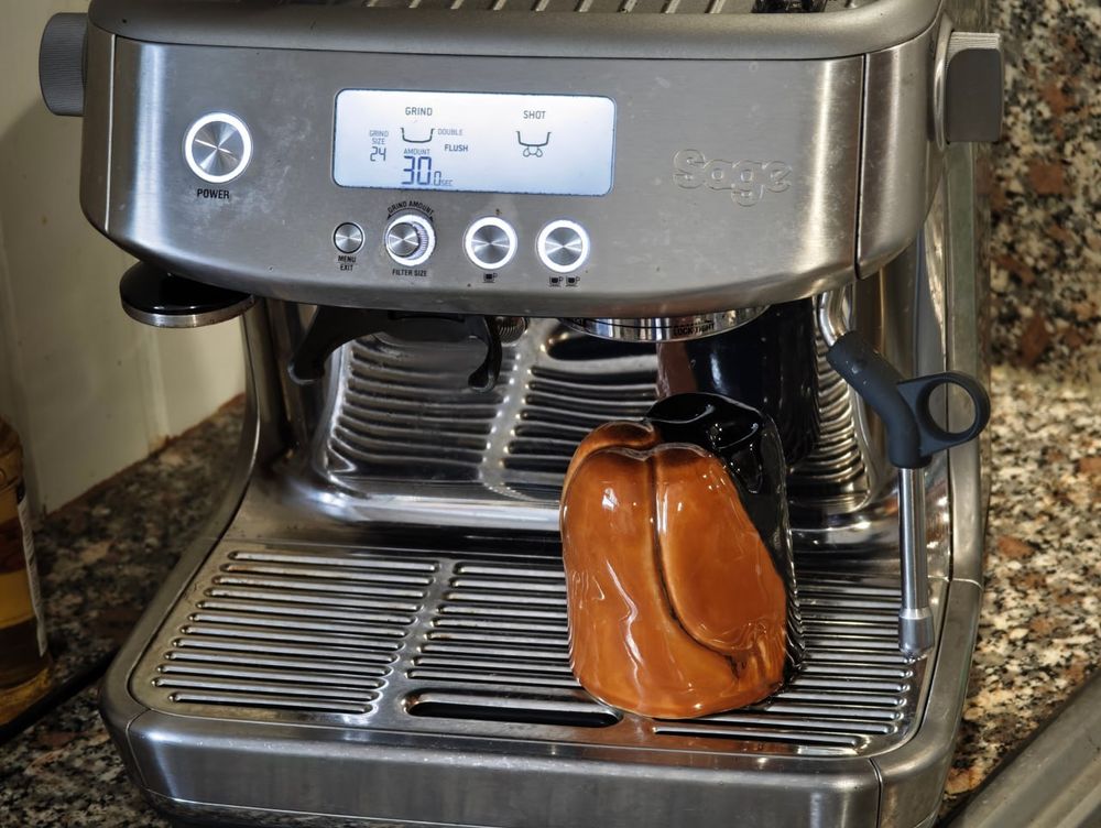 A mug shaped like the snout of a canine (here doberman) with a coffee machine.