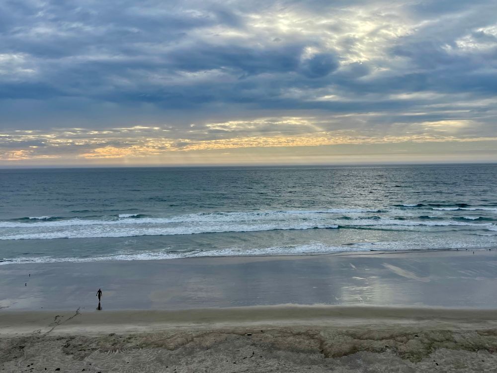 The Pacific Ocean with clouds overhead, and one lone surfer. 