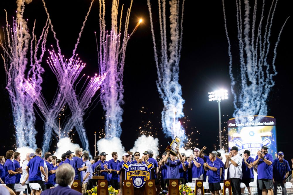 A photo of the LSU baseball team celebrating their victory in the Men's College World Series at Alex Box Stadium June 25, 2025. Fireworks are going off in the sky behind the stage. 