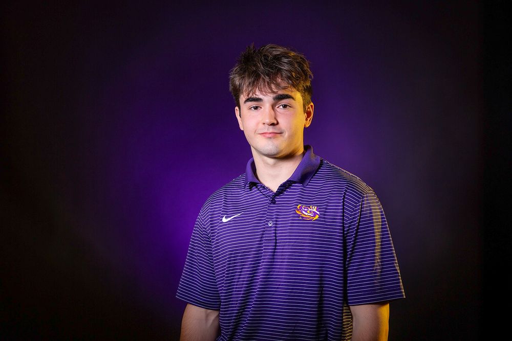 A photo of LSU's 2025 Goldwater Scholar, Gerard Lorio, in a purple LSU shirt photographed on a dark purple background. 