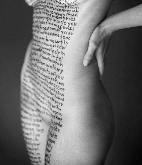 Abstract, monotone, naked female form, mid thigh to under breasts, the front of her body adorned with finely hand written text, which is unreadable. 