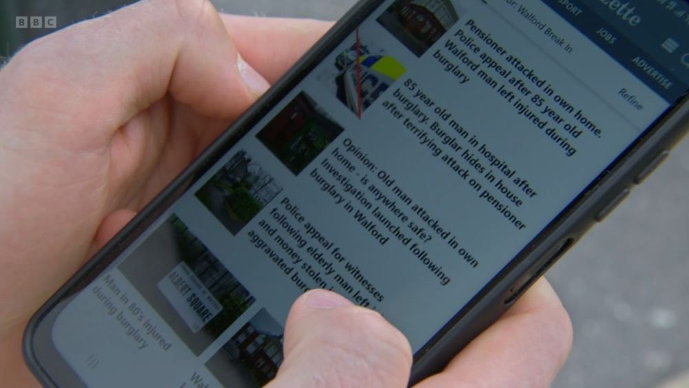 Close up of Oscar Branning holding a phone showing the Walford Gazette website and headlines on a page headed "Walford Break in"

Pensioner attacked in own home. Police appeal after 85 year old Walford man left injured during burglary

85 year old man in hospital after burglary. Burglar hides in house after terrifying attack on pensioner

Opinion: Old man attacked in own home is anywhere safe? Investigation launched following burglary in Walford

Police appeal for witnesses following elderly man left … aggravated burglary… 

Man in 80s injured during burglary