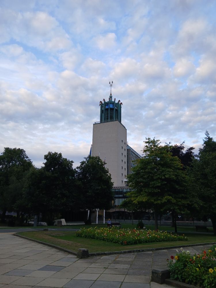 The white tower of the Civic centre with the green turret with the seahorses coming off it. In front of it are trees and gardens 