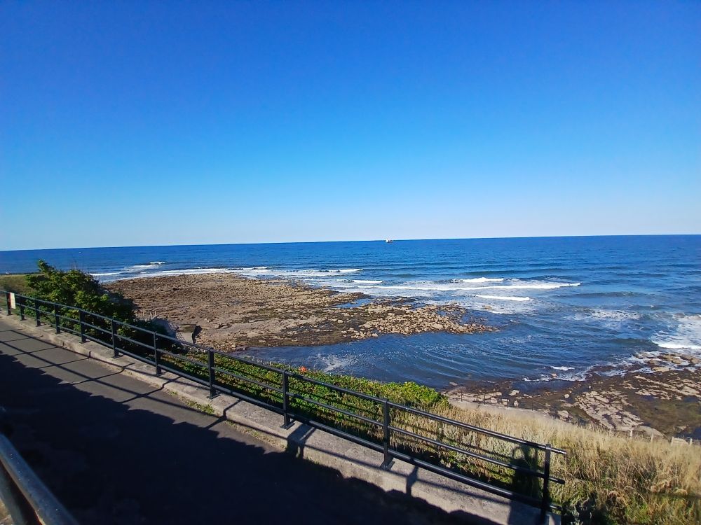 A photo of the very blue north sea, and rocks coming out of it. The sky is very blue