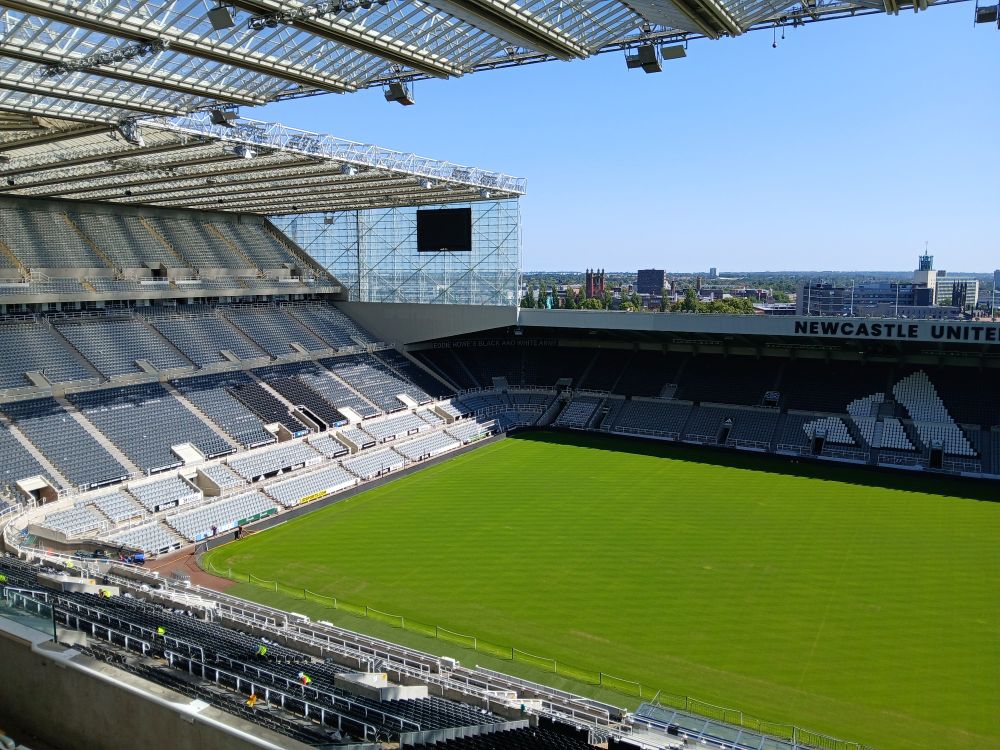 An empty leazes end and east stand, and pitch in st james park. You can see the roof and the wider Newcastle area in the background. This photo was taken from within the stadium on level 7