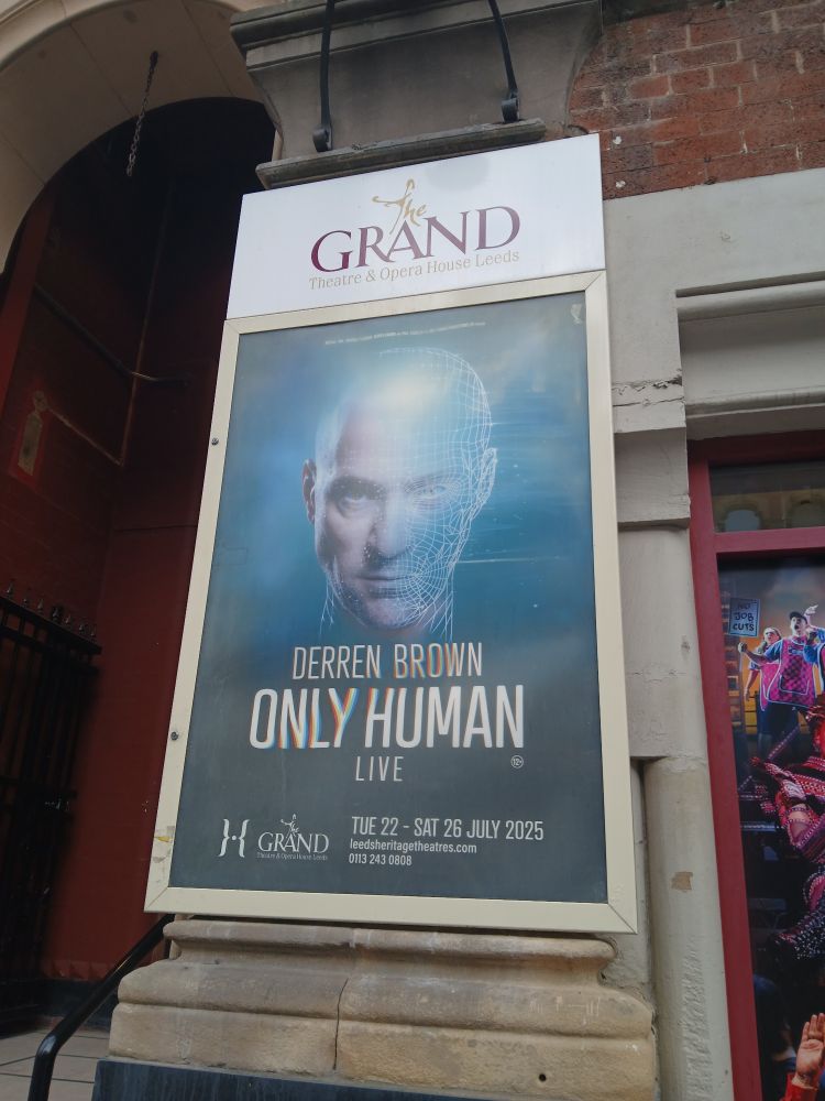 A poster for 'Derren Brown Only Human' featuring the title of the show and a picture of Derren Brown with part of his face turned into computer lines