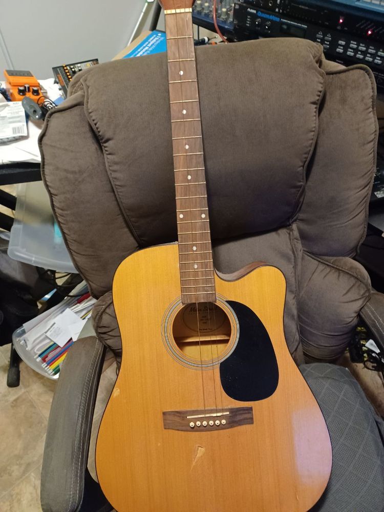 a dreadnaught acoustic guitar with missing strings and body damage