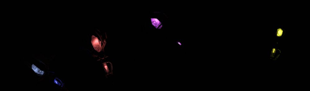 four glowing crystals in a dark void from left to right they are blue, red, purple and yellow