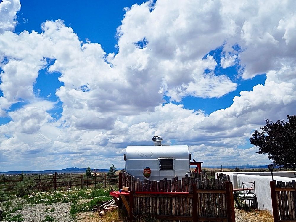 A trailer in the New Mexico desert with a native wooden fence around it. 