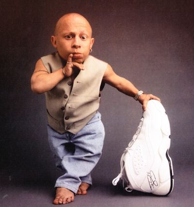 American Actor Verne Troyer holding a shoe that is almost half as tall as he is