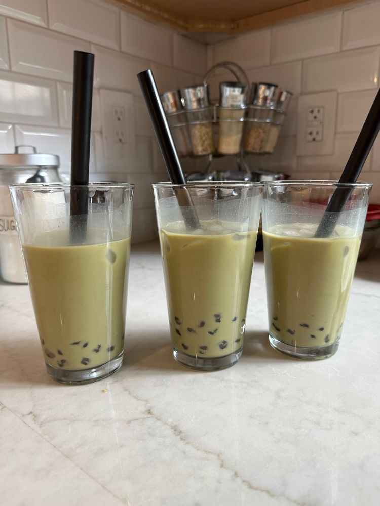 Three glasses of iced matcha latte with boba. 