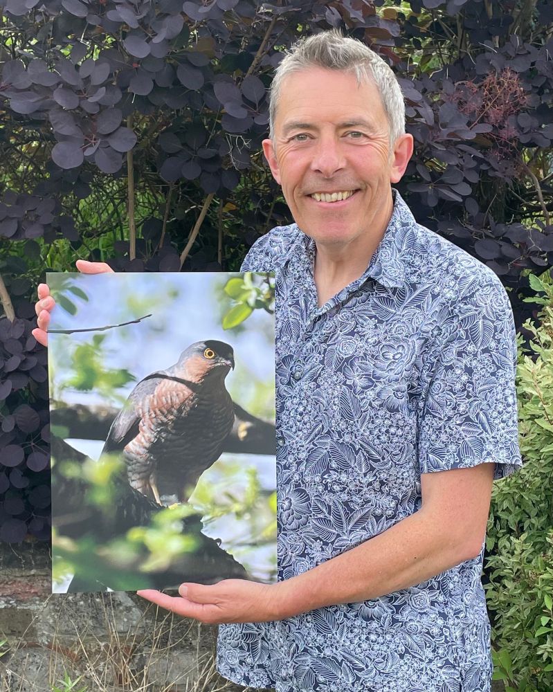 Me holding an A3 sized close up photograph I took of a male sparrowhawk in a tree. 
