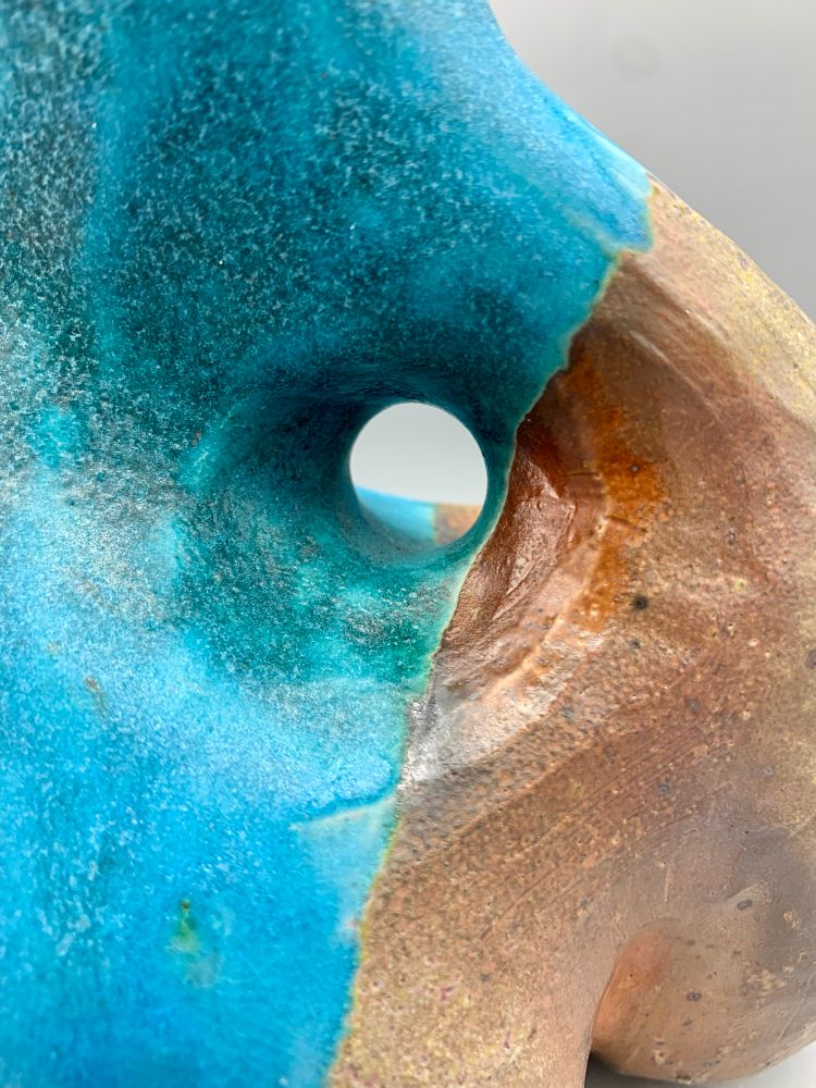 A closeup of a blue and brown, organic shaped, ceramic sculpture