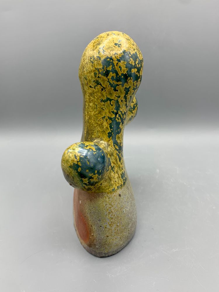 A brown, yellow, and blue organic shaped ceramic sculpture against a grey background.